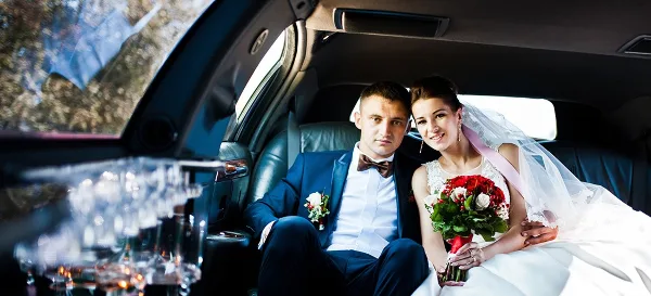 A bride and groom sitting in the back seat of a luxury car.