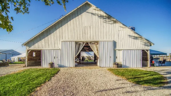 White barn wedding venue with open doors, event setup inside, and surrounding farm property.