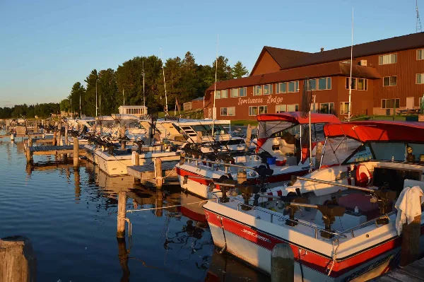 Exterior view of the Sportsman's Lodge building and its dock with fishing boats at sunset.