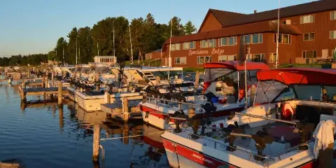 Exterior view of the Sportsman's Lodge building and its dock with fishing boats at sunset.