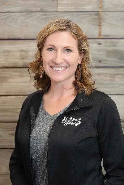 Portrait of Samantha Belonga, owner of St. Ignace in Bloom, wearing a black jacket with the business logo.