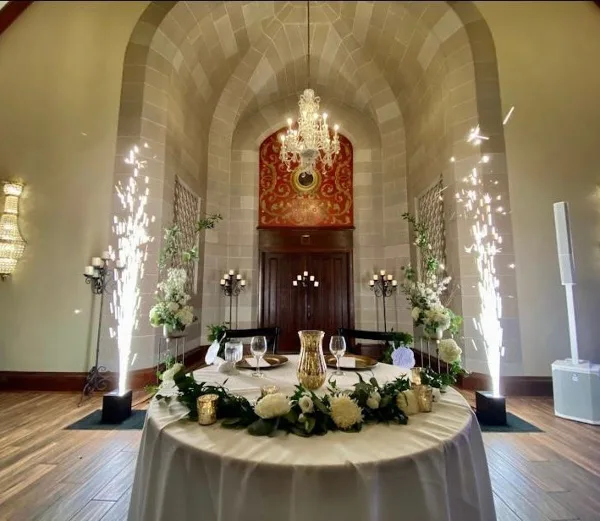 Interior view of a historic event venue featuring a vaulted ceiling, a chandelier, and a round table set with white floral arrangements.