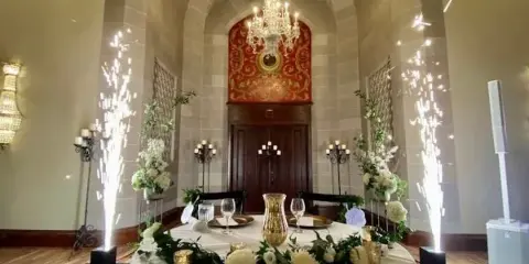 Interior view of a historic event venue featuring a vaulted ceiling, a chandelier, and a round table set with white floral arrangements.