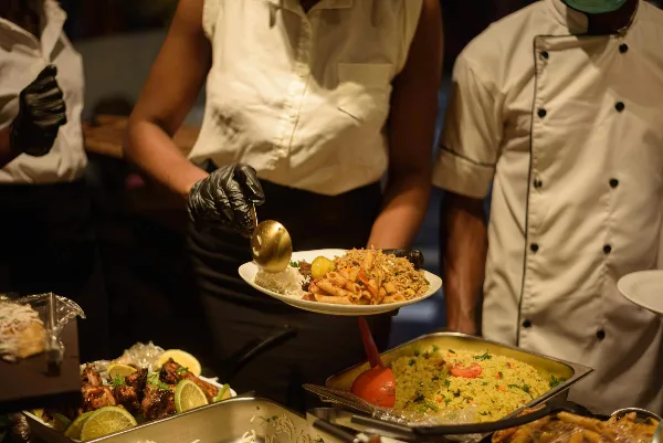 Catering staff serving plated food from a buffet line