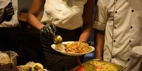 Catering staff serving plated food from a buffet line