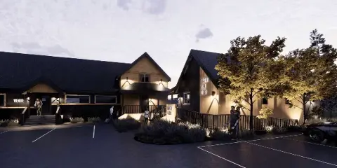 Exterior view of Shasta View Lodge cabins and venue building at dusk with people walking near the entrance.