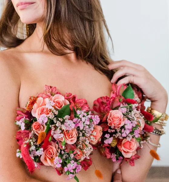 A close-up of a woman holding a large, colorful floral bouquet with pink roses and alstroemeria.