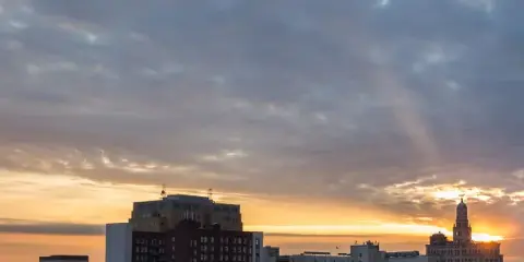 Sunset view of the Davenport, Iowa city skyline featuring the historic clock tower and surrounding buildings.