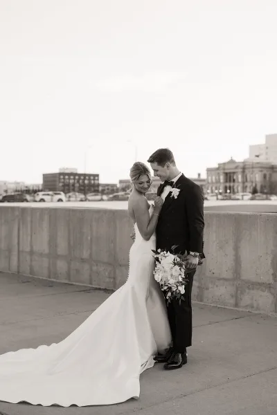 A black and white photograph of a bride and groom standing together outdoors.