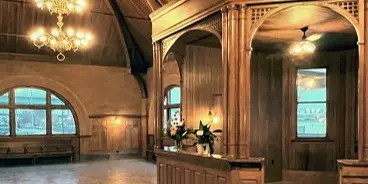 Interior of the Keokuk Union Depot waiting room featuring a high wooden cathedral ceiling, chandeliers, and an octagonal wooden ticket booth.
