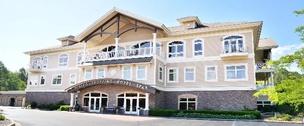 Exterior view of the Riverwalk Place Resort & Spa building featuring a large beige facade, stone foundation, and a covered entrance.