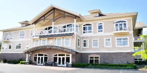 Exterior view of the Riverwalk Place Resort & Spa building featuring a large beige facade, stone foundation, and a covered entrance.