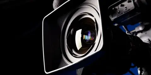 Close-up of a professional video camera lens and equipment.