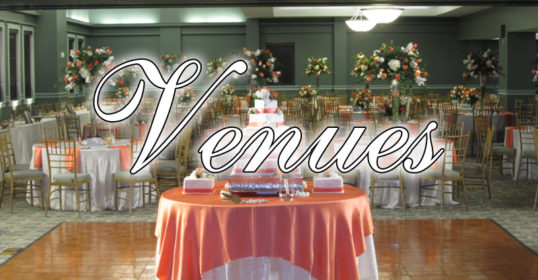 A banquet hall set up for a wedding with round tables, floral centerpieces, and a wedding cake.