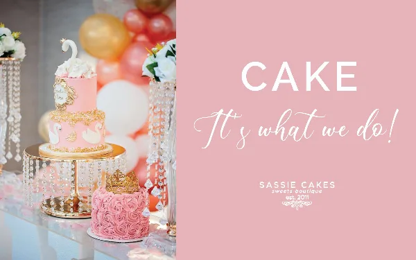 A pink two-tier buttercream wedding cake with white swan toppers and gold accents displayed on a crystal stand next to a smaller pink rose cake with a gold crown.