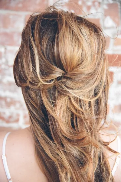Close-up of a woman's back showing a styled, loose bridal updo with wavy hair.