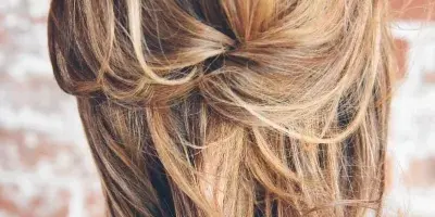Close-up of a woman's back showing a styled, loose bridal updo with wavy hair.