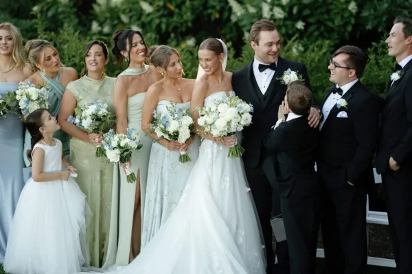 A wedding party, including the bride and groom, posing for a group portrait outdoors.