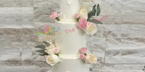 A three-tier white wedding cake decorated with pink and white roses and a Mr & Mrs topper.