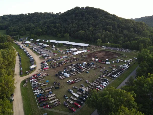 Aerial view of the Wabasha County Fairgrounds showing the event center, grandstand, and parking areas surrounded by forested hills.