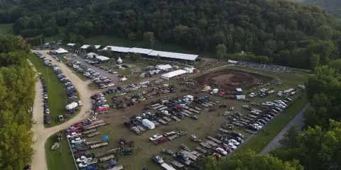 Aerial view of the Wabasha County Fairgrounds showing the event center, grandstand, and parking areas surrounded by forested hills.