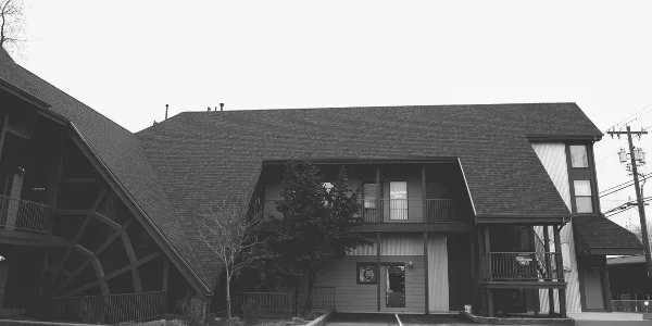Black and white exterior view of the Charlotte's Web Building, a mid-century structure with a steep roof and wooden web design, serving as the Fly the Coop wedding chapel.