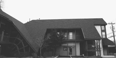 Black and white exterior view of the Charlotte's Web Building, a mid-century structure with a steep roof and wooden web design, serving as the Fly the Coop wedding chapel.