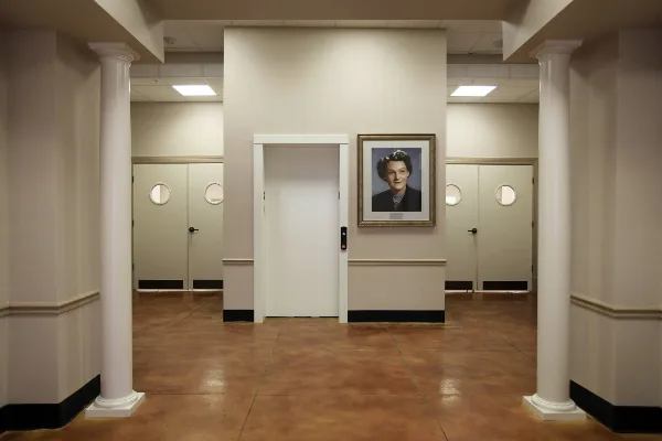 Interior view of the Clista A. Calhoun Center showing the elevator, white columns, and a framed portrait of Clista A. Calhoun on the wall.