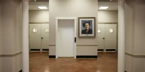 Interior view of the Clista A. Calhoun Center showing the elevator, white columns, and a framed portrait of Clista A. Calhoun on the wall.