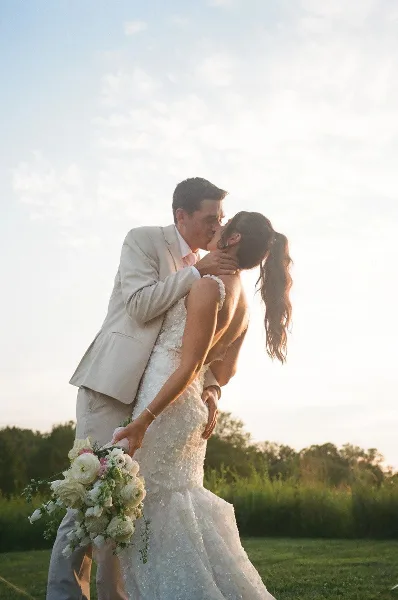 A bride and groom sharing a kiss outdoors during a wedding ceremony.