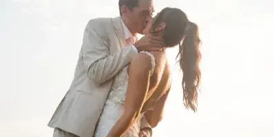 A bride and groom sharing a kiss outdoors during a wedding ceremony.