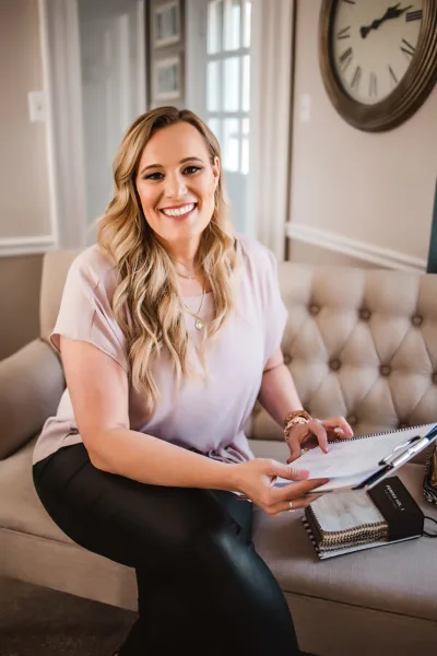 Lisa VanHorton, a wedding planner, smiling while holding a clipboard in an office setting.