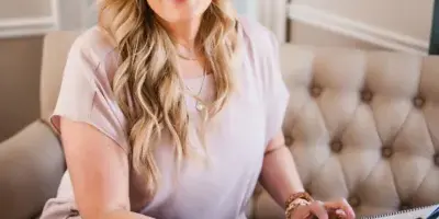Lisa VanHorton, a wedding planner, smiling while holding a clipboard in an office setting.