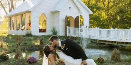 Bride and groom kissing in front of a white open-air chapel at a wedding venue