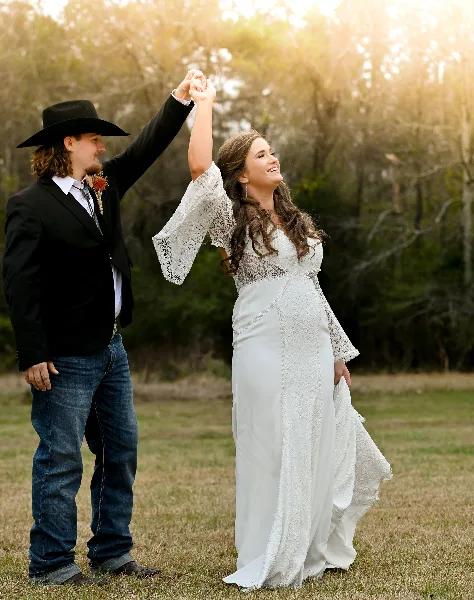 A bride and groom dancing outdoors in a field during a wedding.