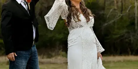 A bride and groom dancing outdoors in a field during a wedding.