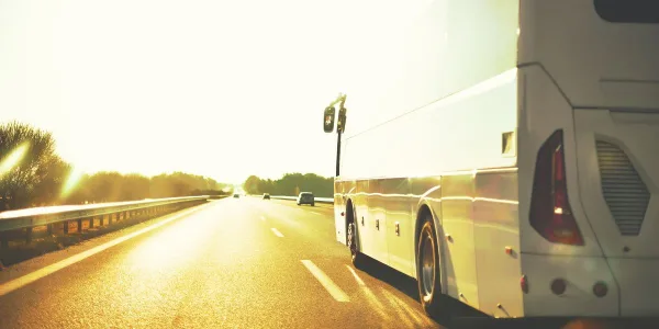 A large white charter bus driving on a highway during the day.