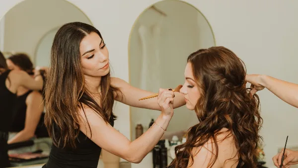 A makeup artist applying makeup to a client's face in a studio setting.