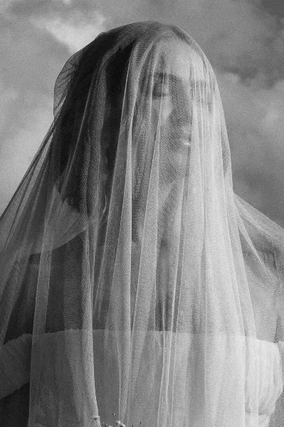 Black-and-white portrait of a bride with a veil over her face