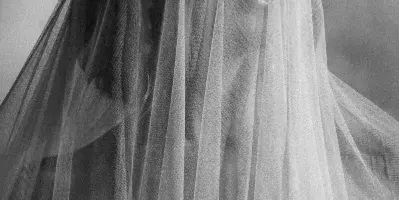 Black-and-white portrait of a bride with a veil over her face