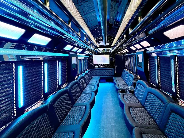 Interior view of a luxury party bus with blue LED lighting and leather seating.