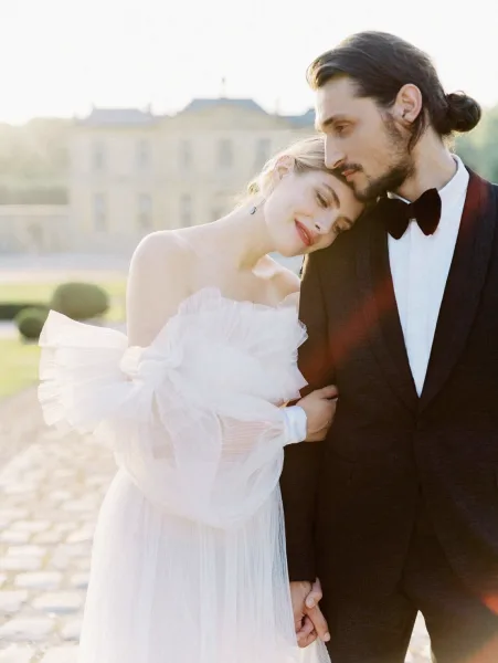 A bride and groom embracing in a formal wedding portrait outdoors.
