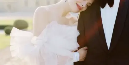A bride and groom embracing in a formal wedding portrait outdoors.