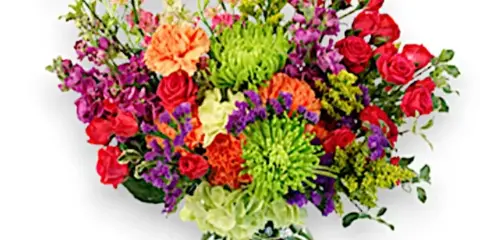 A colorful mixed bouquet of fresh flowers, including roses and chrysanthemums, arranged in a clear glass vase.