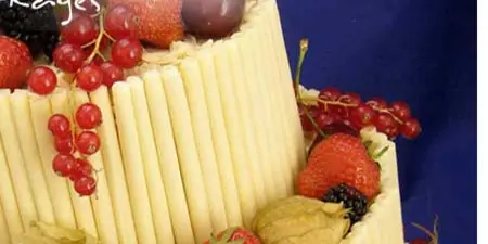 A tiered catering display featuring fresh strawberries, grapes, and blackberries arranged on a base of vertical pastry sticks.