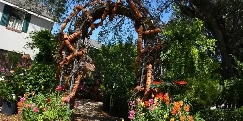 Outdoor garden area featuring a decorative arch, potted plants, and flowers at a florist shop.