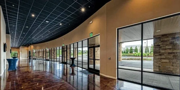 Interior view of a modern event venue lobby with polished floors, glass doors, and a curved ceiling.