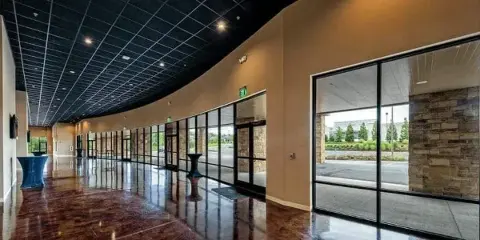 Interior view of a modern event venue lobby with polished floors, glass doors, and a curved ceiling.