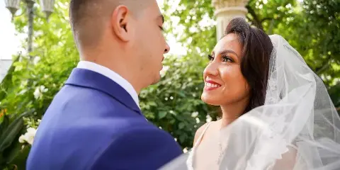 A bride and groom looking at each other during a wedding ceremony outdoors.