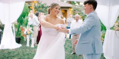A bride and groom dancing under a semi-clear top tent at an outdoor wedding venue.